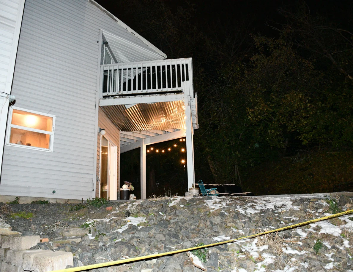 Rear house exterior with an upper balcony, posts and string lights.