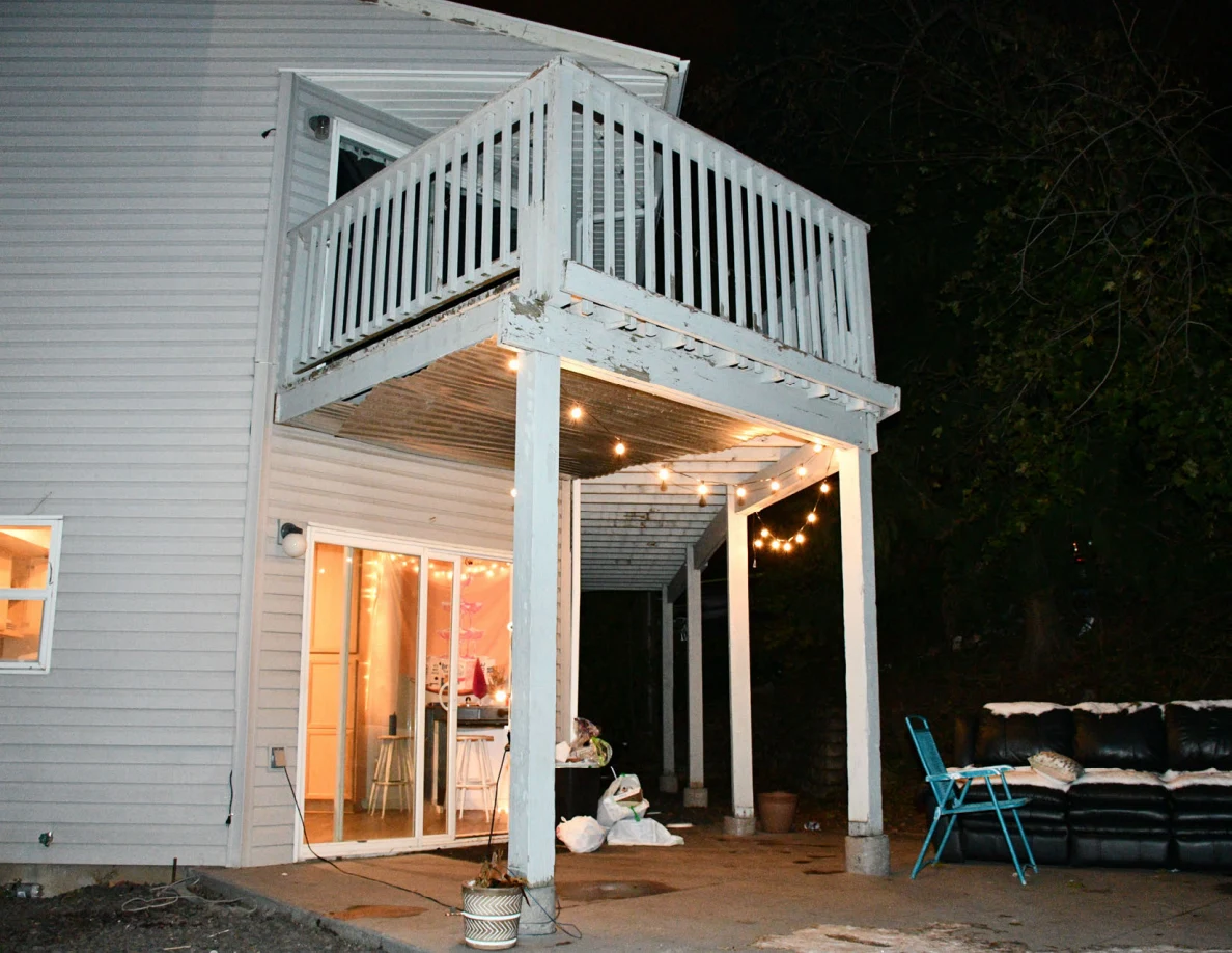 Rear patio with sliding glass door, balcony, string lights, folding chair and sofa.