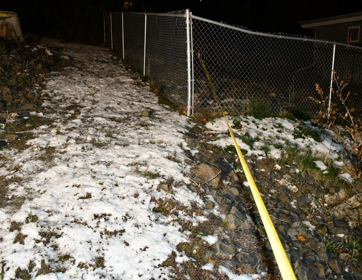 Chain-link fence beside snow-covered ground and yellow barrier tape.
