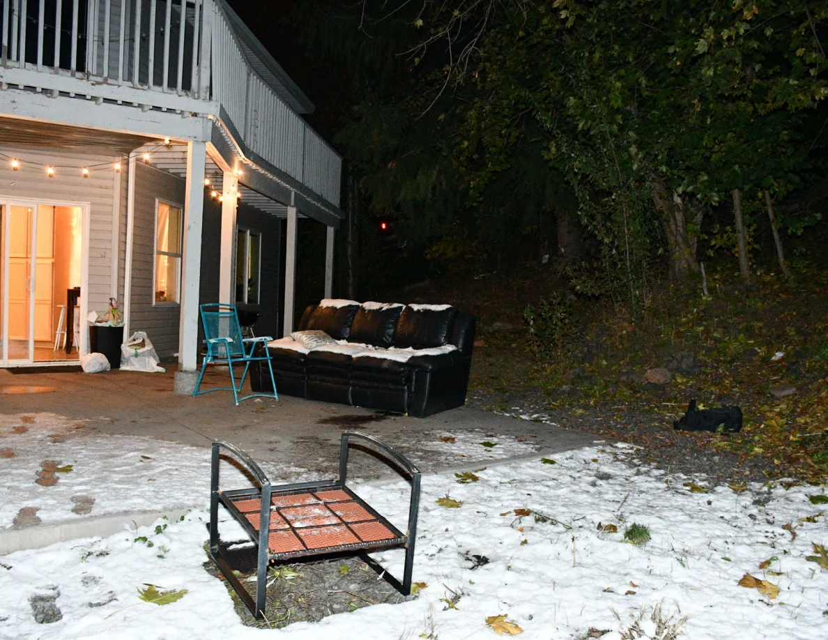 Patio chair in snow with a sofa, folding chair and sliding glass door behind it.