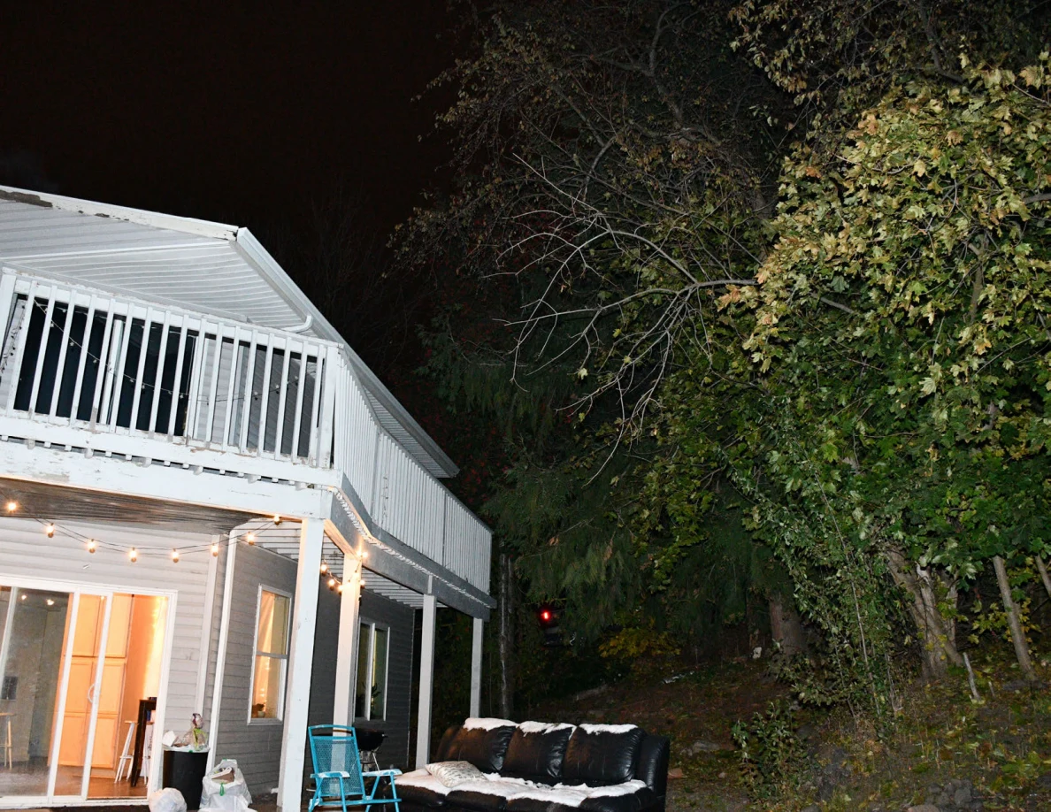 Rear balcony and patio with sofa, folding chair and trees.