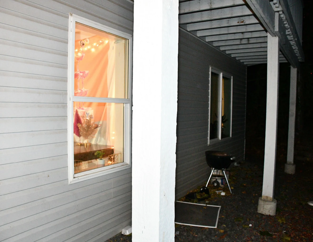 House windows and patio posts with a kettle barbecue grill beneath the balcony.