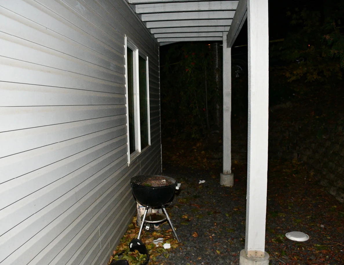 Kettle barbecue grill beside the house wall and a patio post.