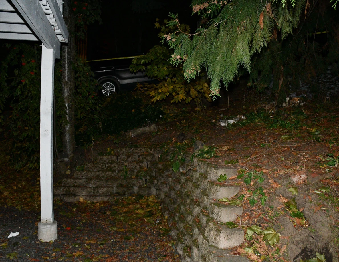 Retaining wall, trees and vehicle beyond the patio posts.