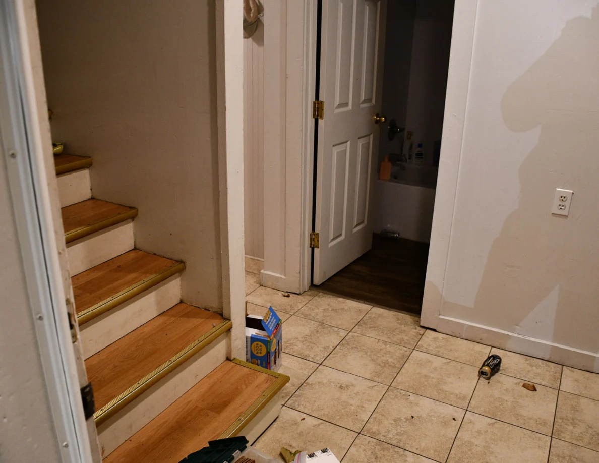 Entryway tile floor, wooden stairs and an open bathroom doorway.