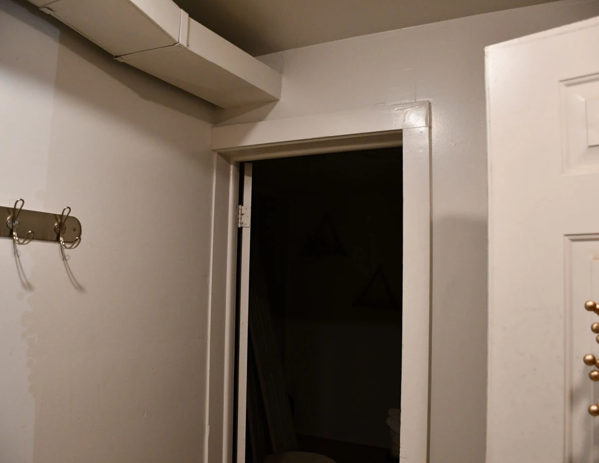 Wall hooks and open doorway beneath exposed ductwork.