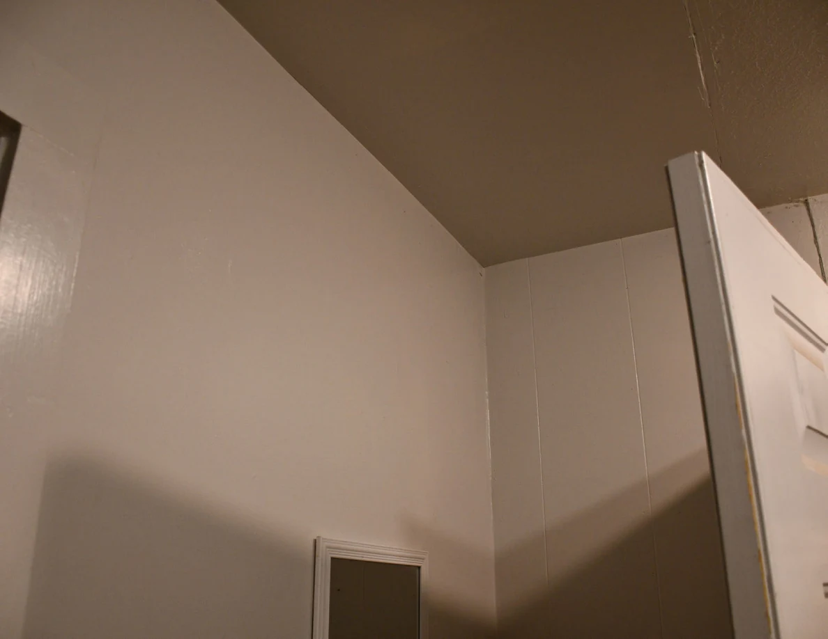 Upper entryway wall, mirror edge and open door.
