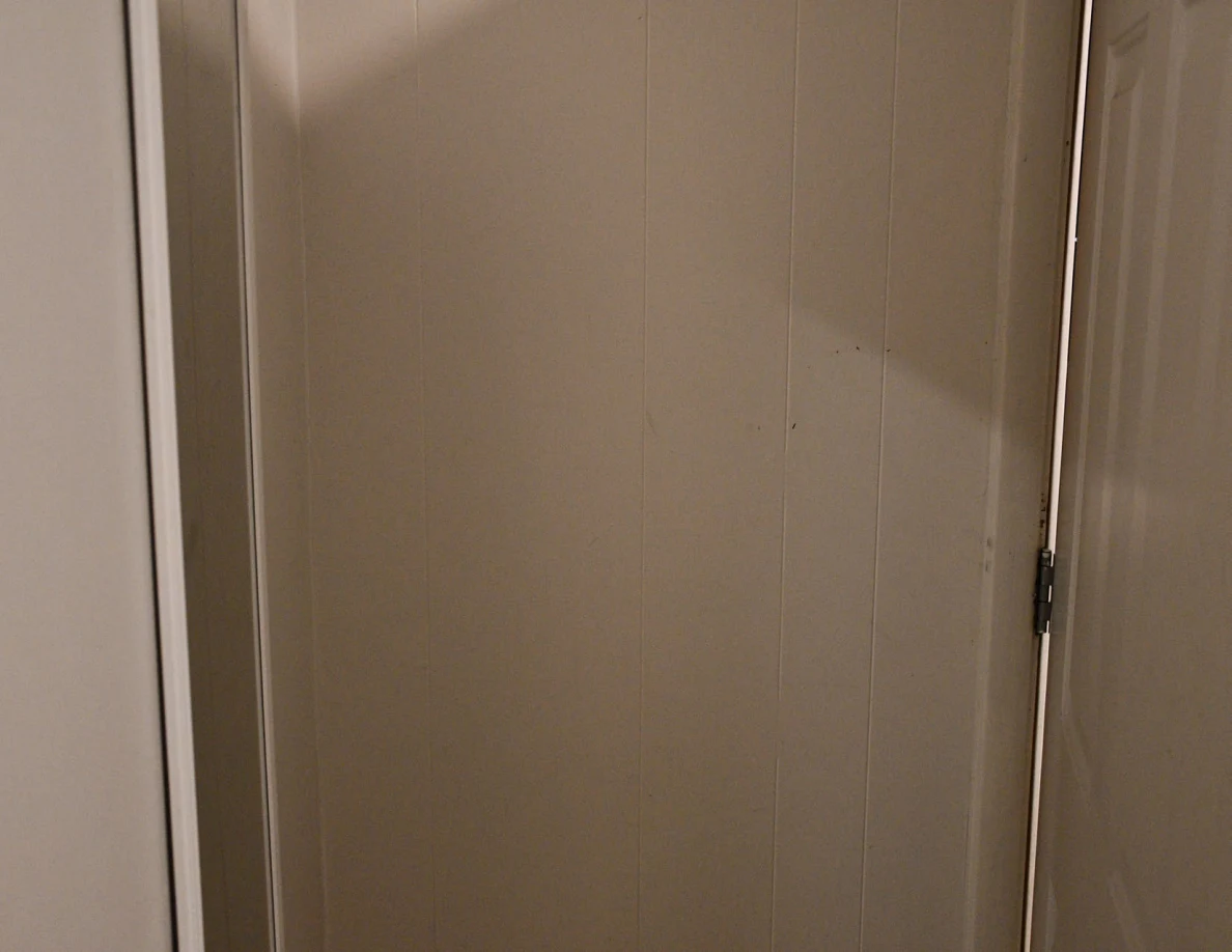 Close view of an interior wall beside the door hinge.