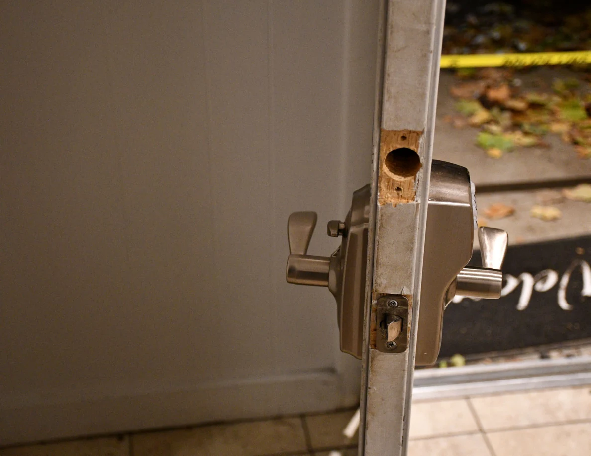 Door edge with latch hardware and a circular opening above it.