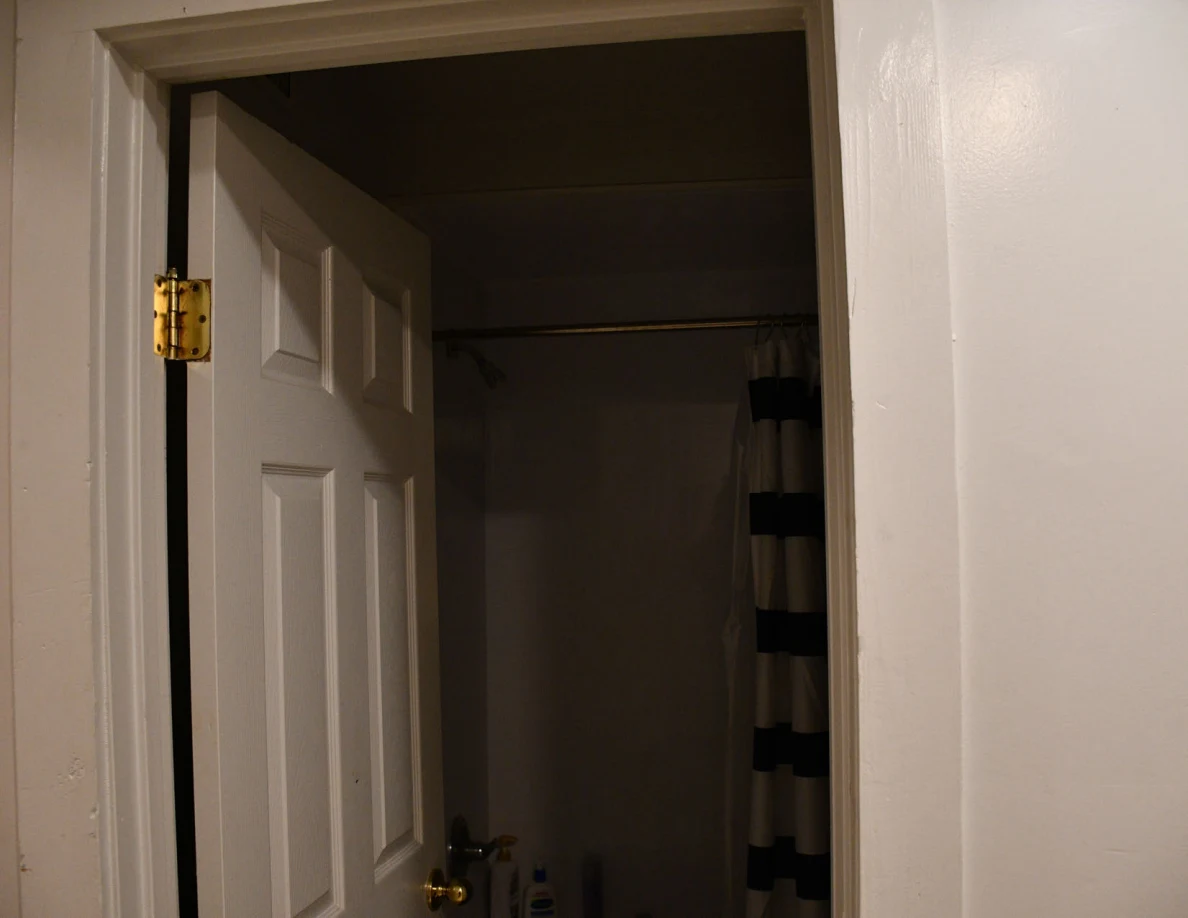 Upper bathroom doorway and shower curtain in a dim interior.