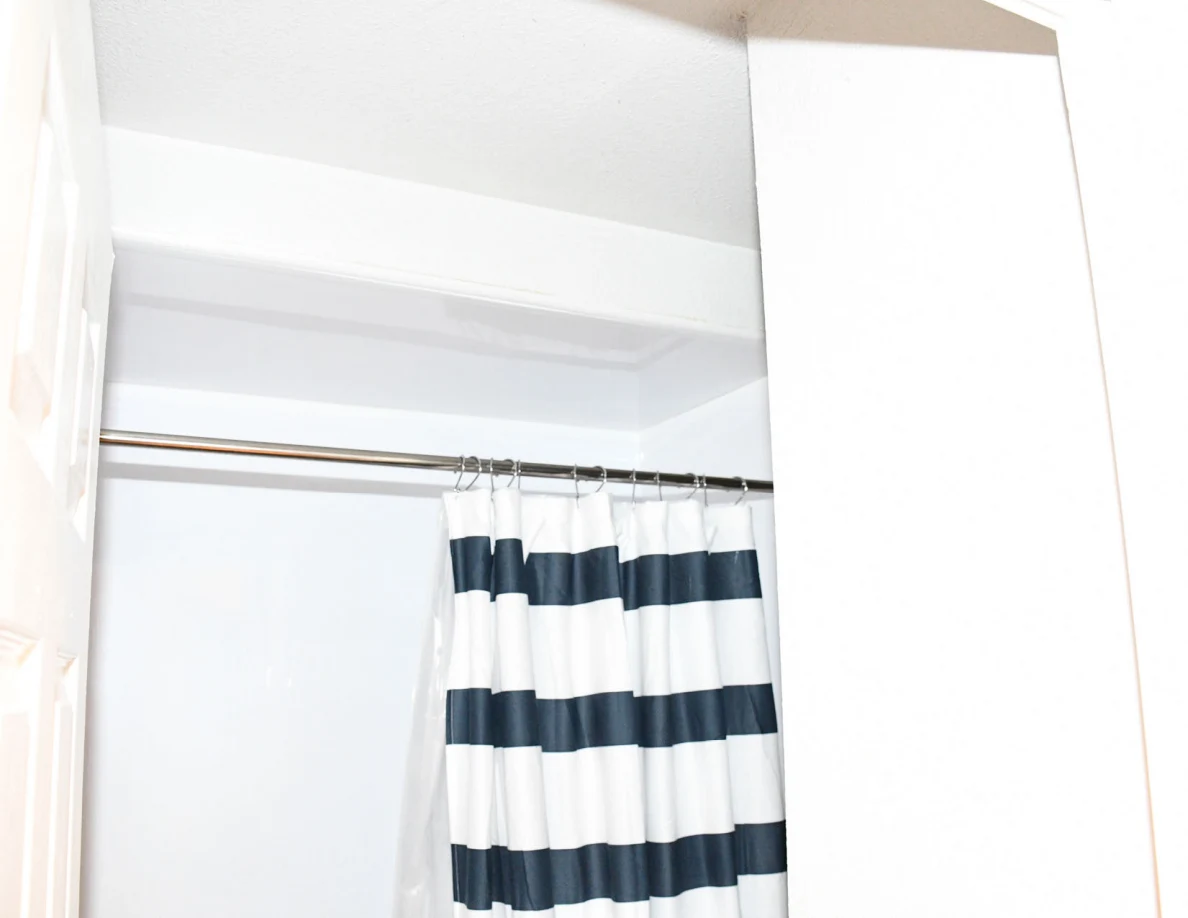 Upper bathtub surround and striped shower curtain on a rod.