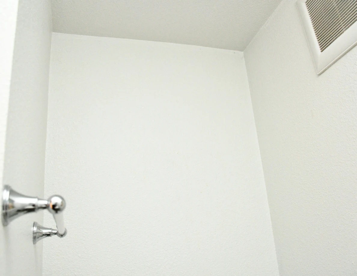 Upper bathroom wall, ceiling corner and vent.