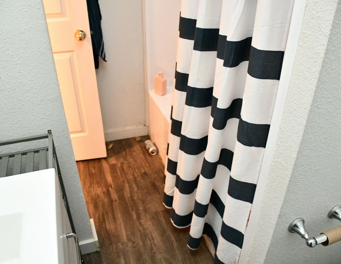 Bathroom floor, striped shower curtain and open doorway.
