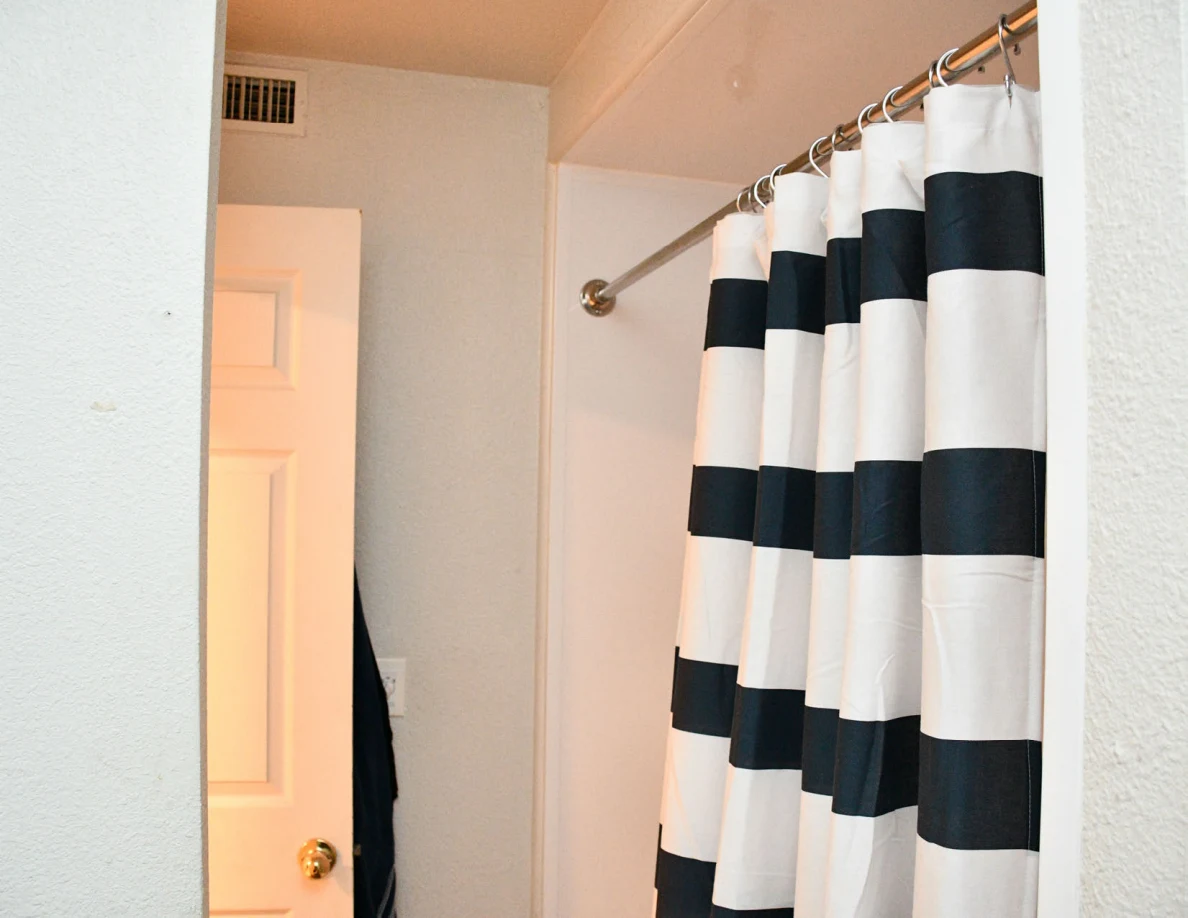 Striped shower curtain, curtain rod and upper bathroom doorway.