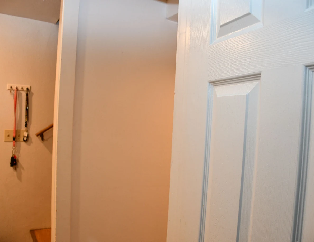 Interior doorway beside wall hooks and hanging straps.