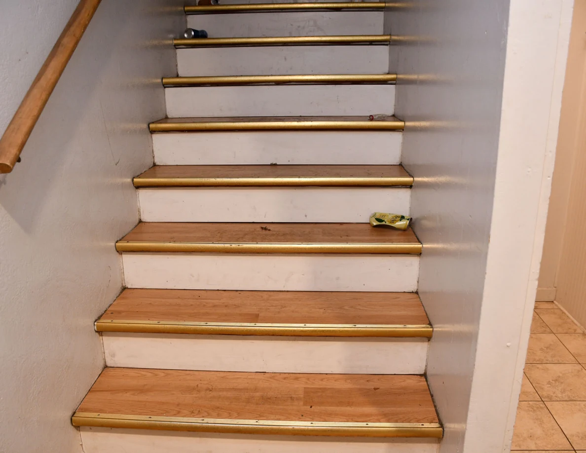 Wooden staircase with handrail and small objects on steps.