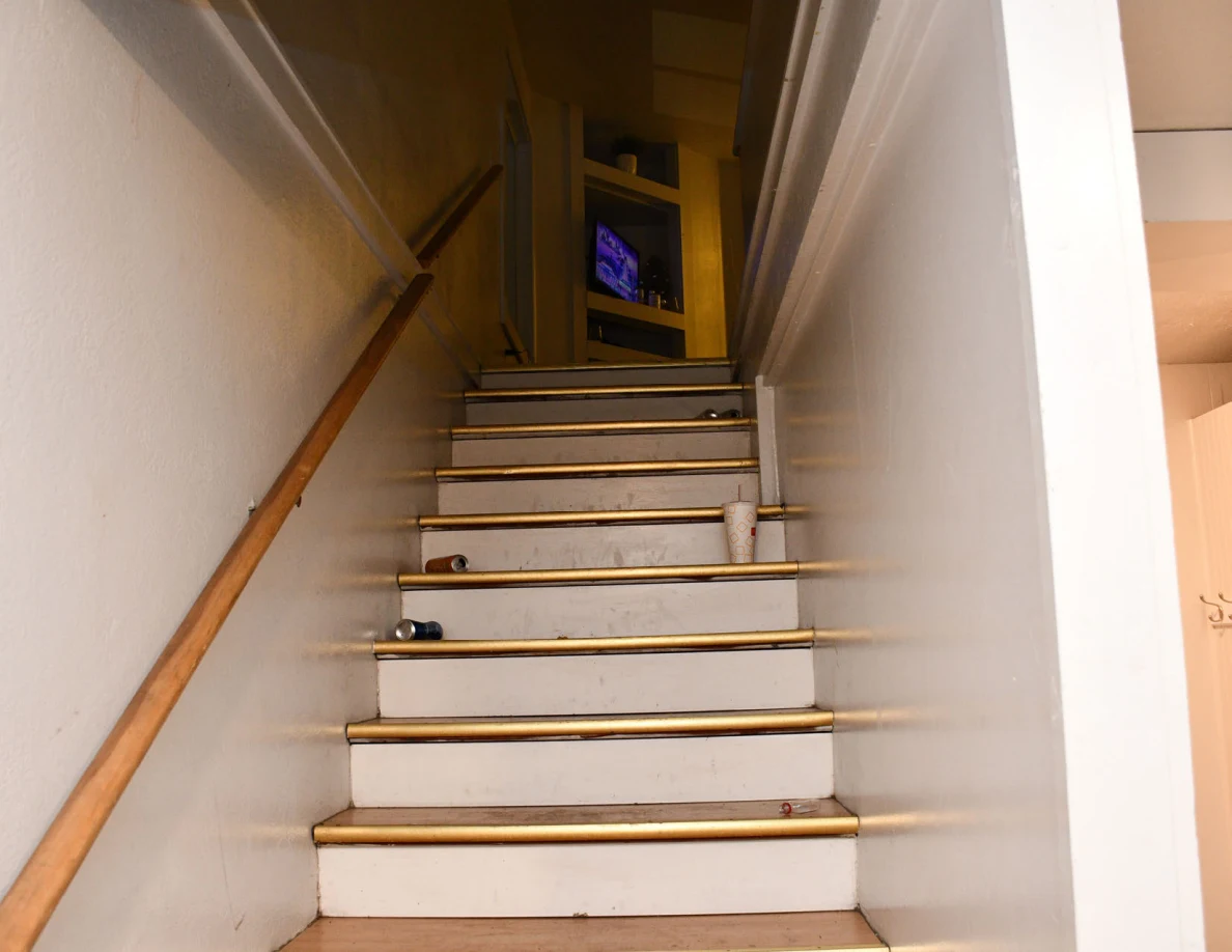 Wooden stairs leading up toward a room with a television.