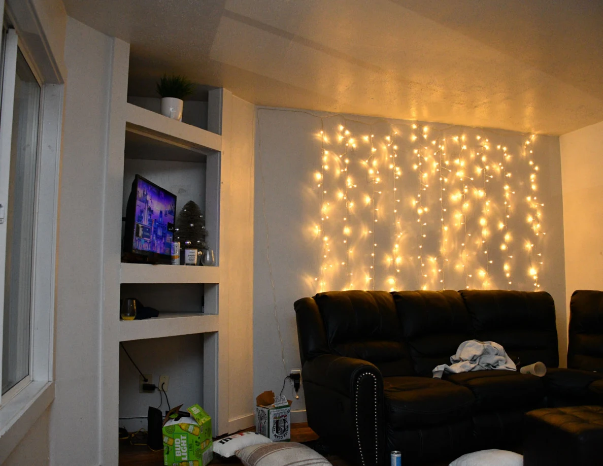 Living room television shelving and black sofa beneath string lights.