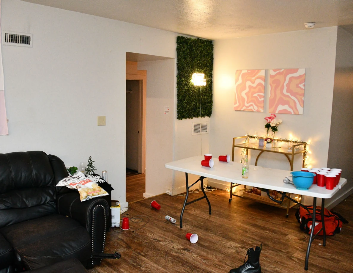 Living room with folding table, red plastic cups, sofa, wall artwork and console table.