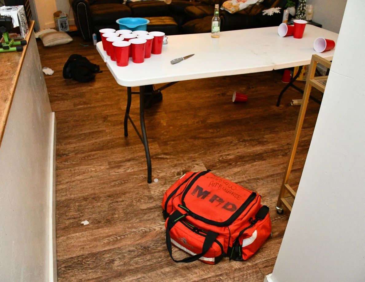 White folding table with red cups and a small knife; red equipment bag on the floor.