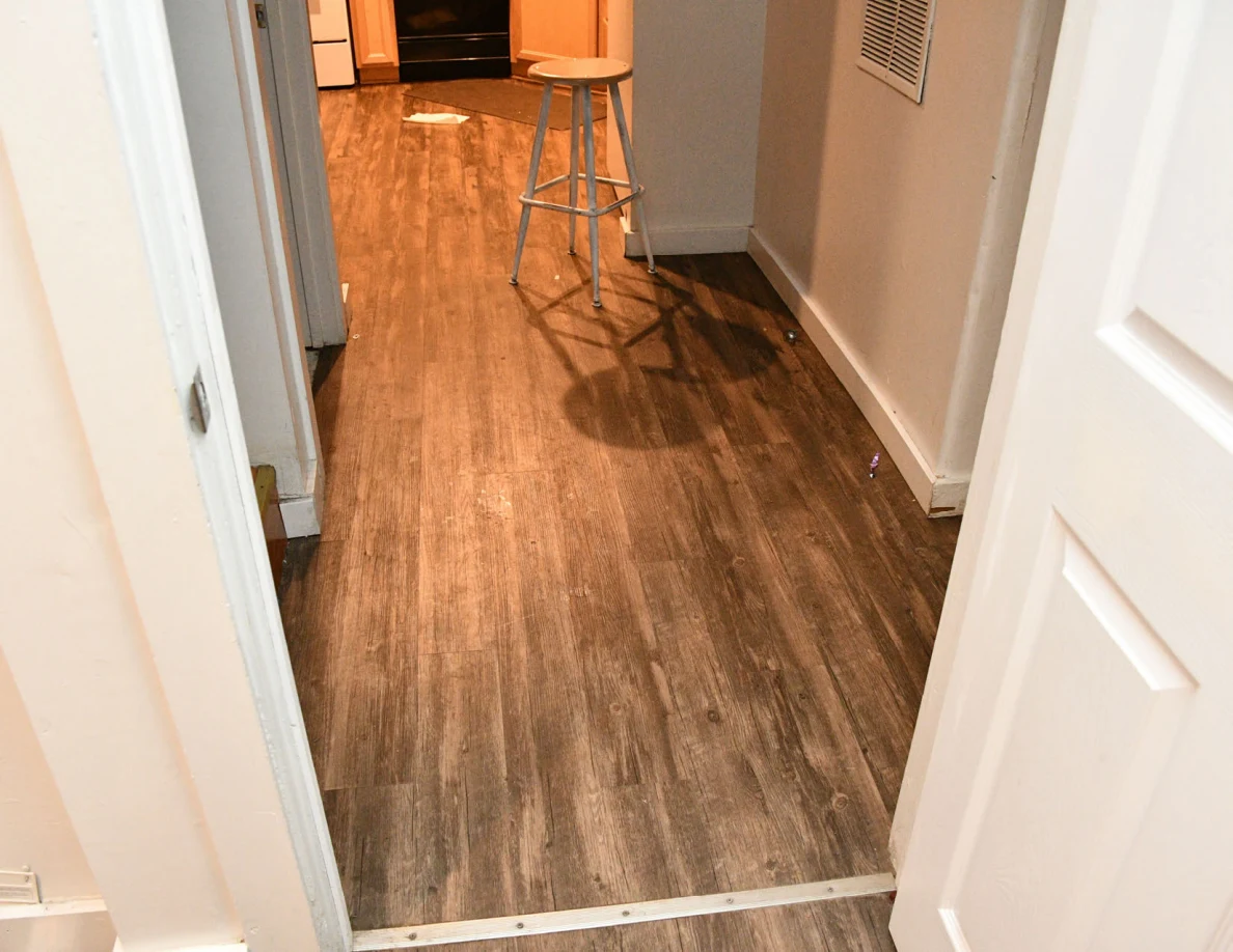 Hallway floor leading toward a kitchen and a round stool.