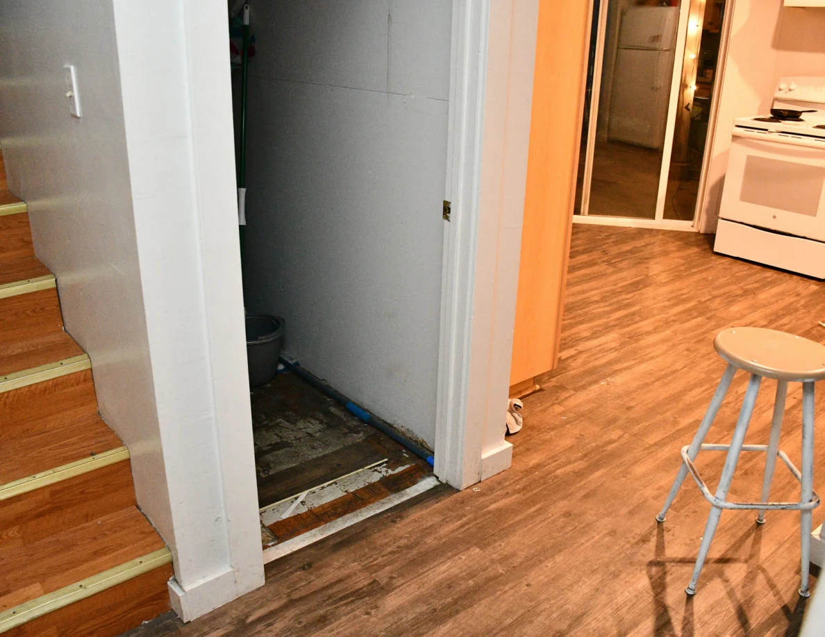 Wooden stairs, open closet and kitchen area with stool and stove.