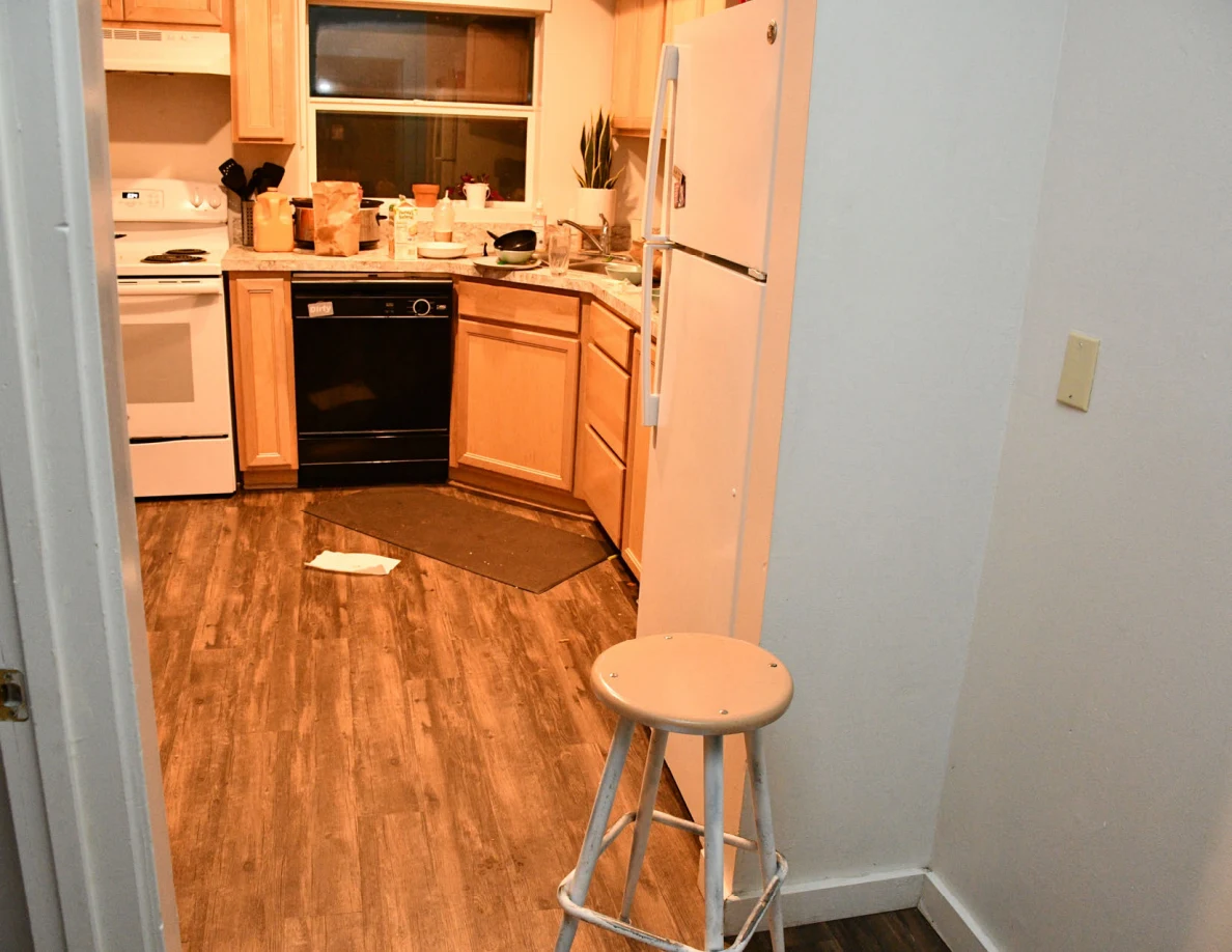 Kitchen with refrigerator, stove, dishwasher, cabinets and a round stool.