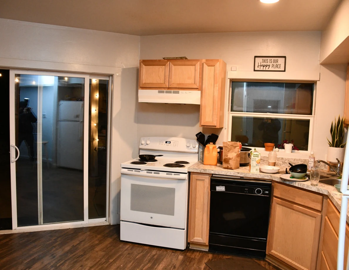 Kitchen stove, dishwasher, sink area, cabinets and sliding glass door.