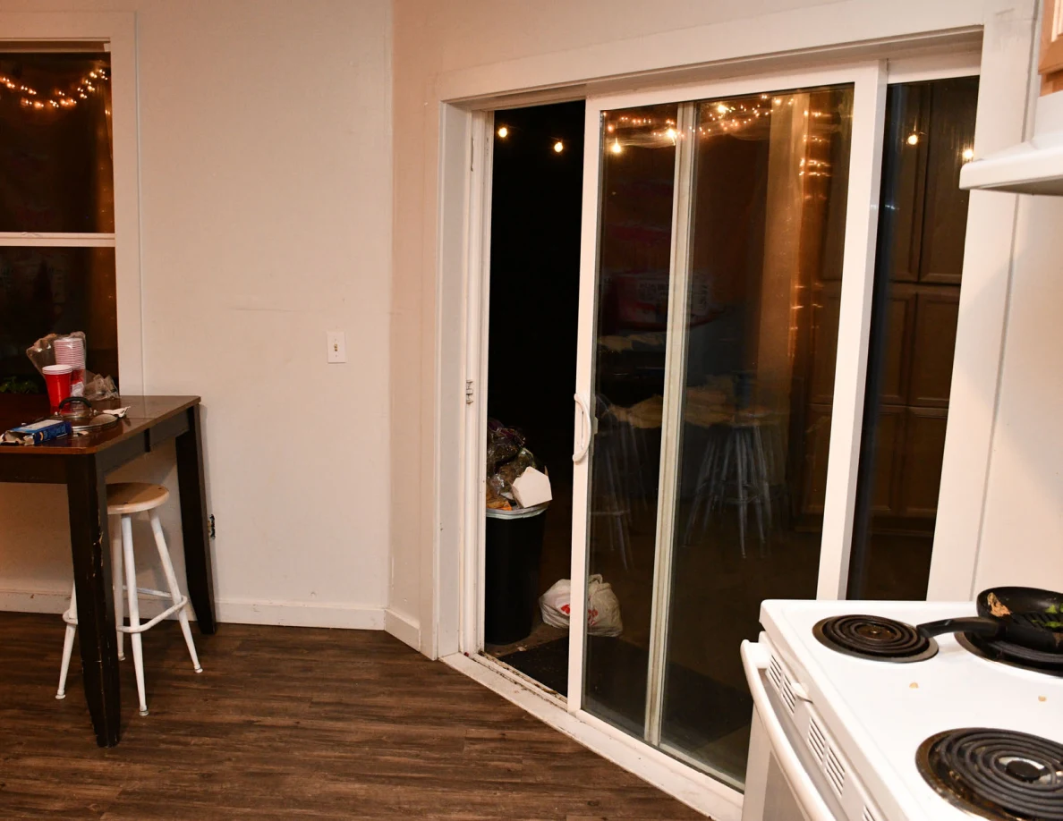 Kitchen sliding glass door beside stove and a tall table with stools.