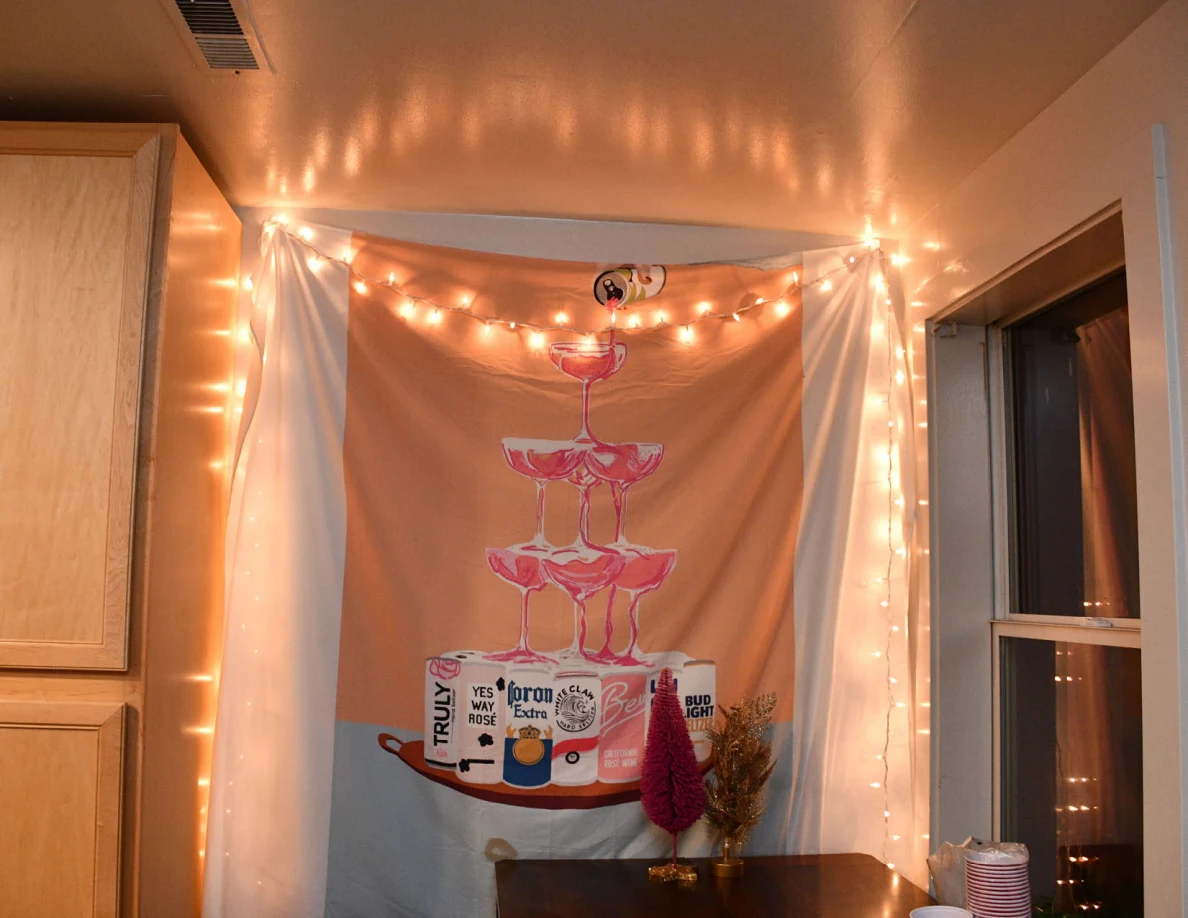 Decorative hanging fabric with drink illustrations framed by string lights.