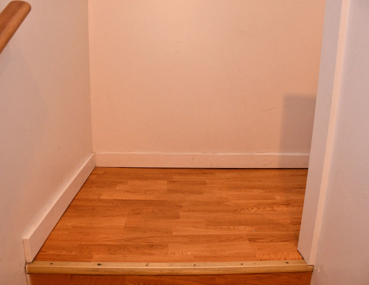Wooden stair landing and plain interior wall.