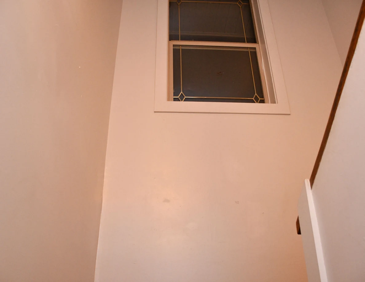 Stairwell window above a wooden landing.