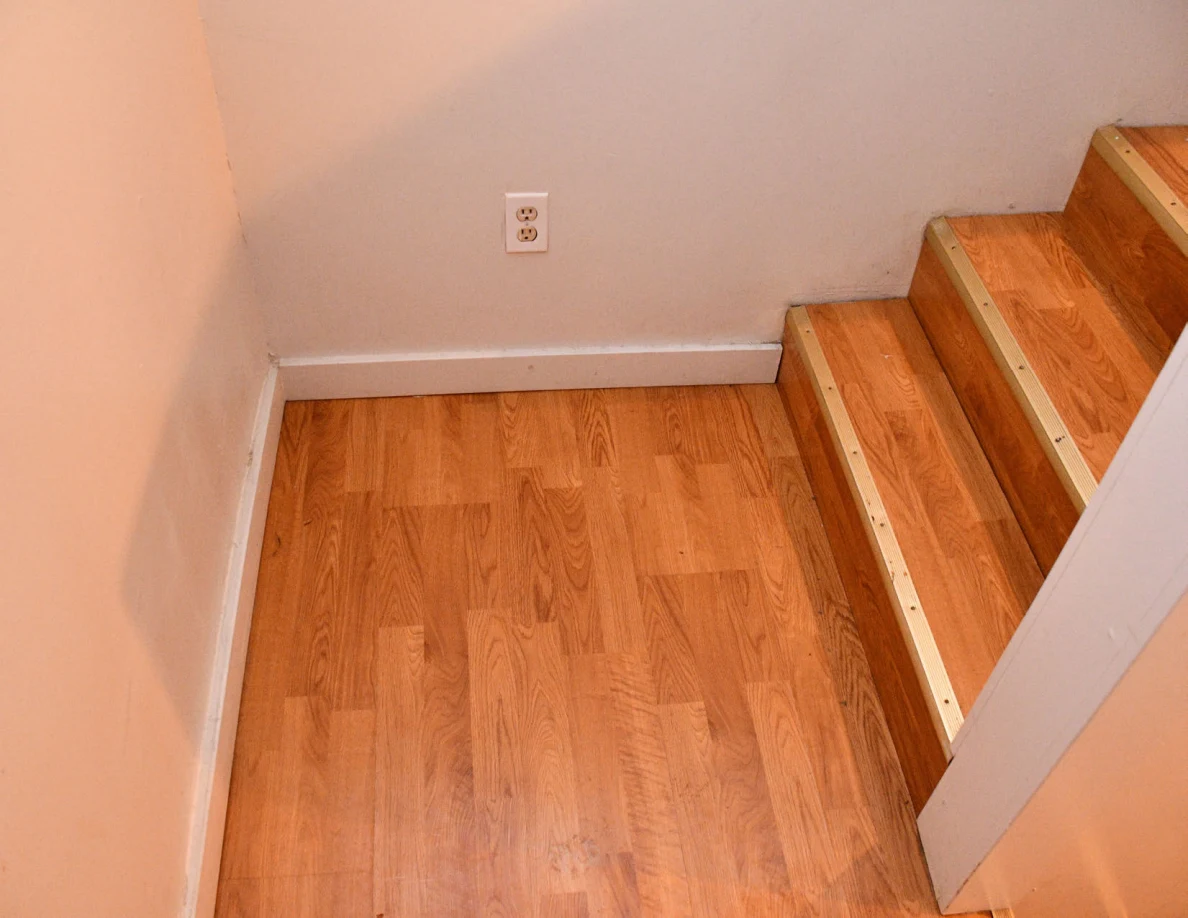 Wooden stair landing and steps beside an electrical outlet.