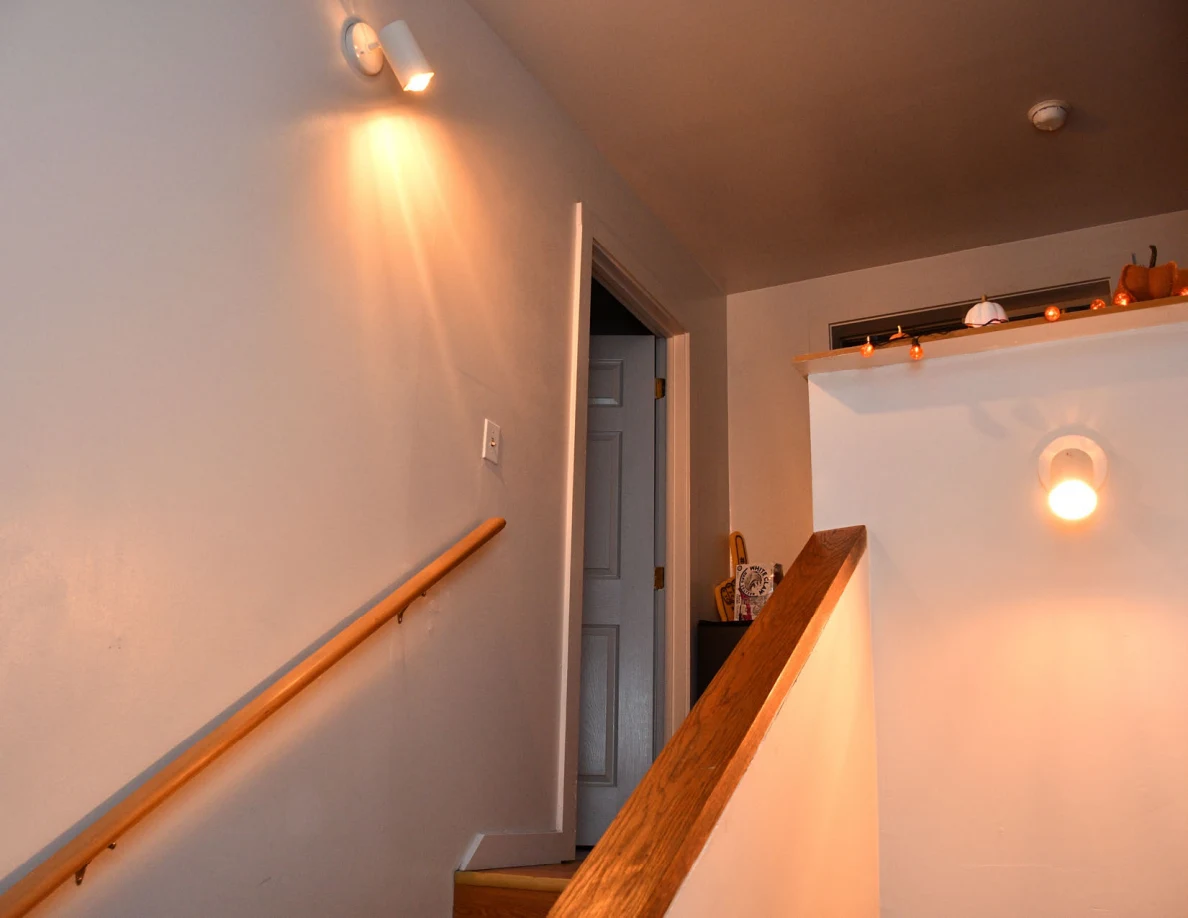 Upper stairwell, wall lights, doorway and landing rail.