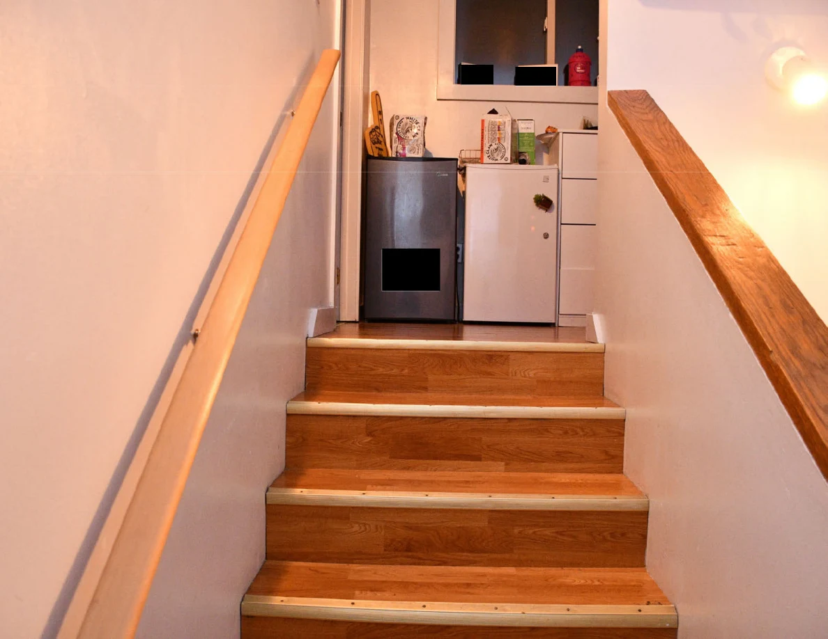 Wooden steps leading to a landing with compact refrigerators and drawers.