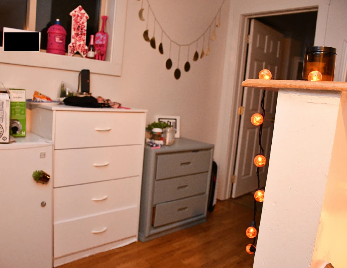 White and gray drawer units, compact refrigerator and hanging moon-shaped decoration.