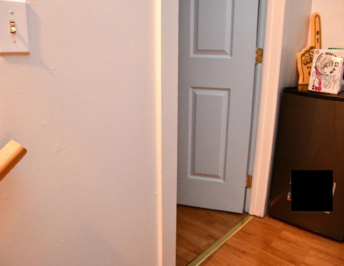 Doorway and wooden landing beside a compact refrigerator.