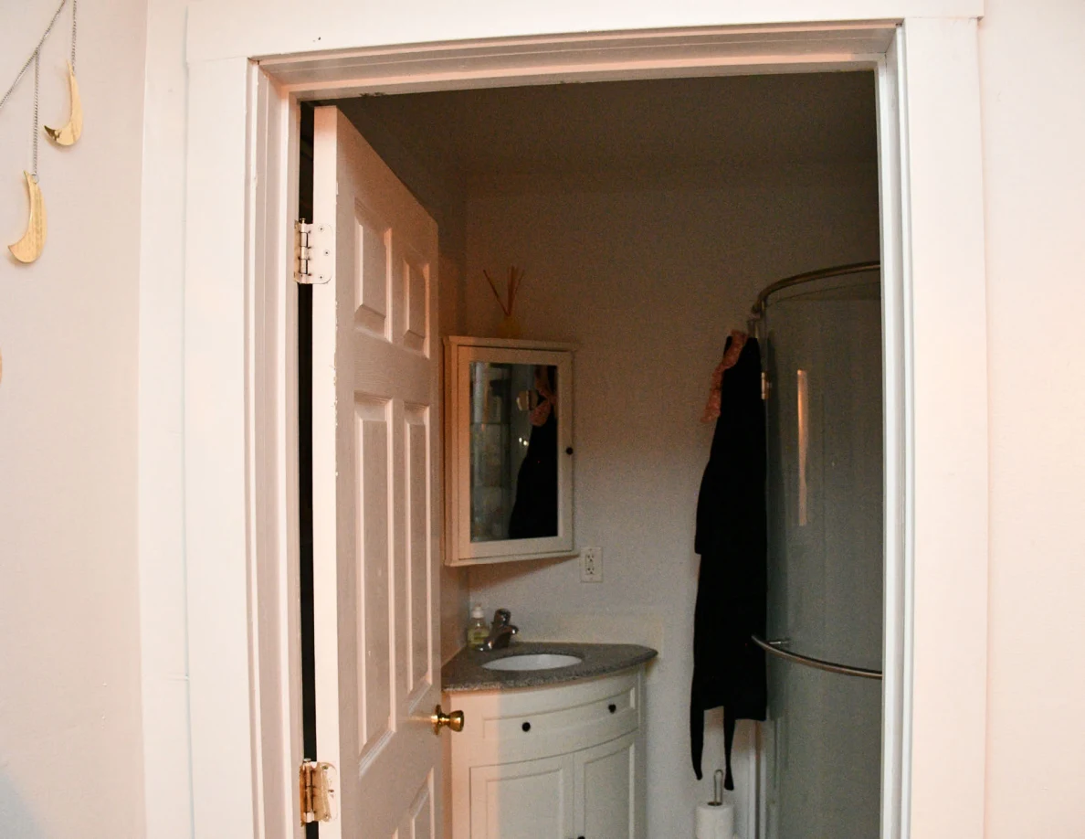 Bathroom mirror, corner sink and curved shower enclosure.