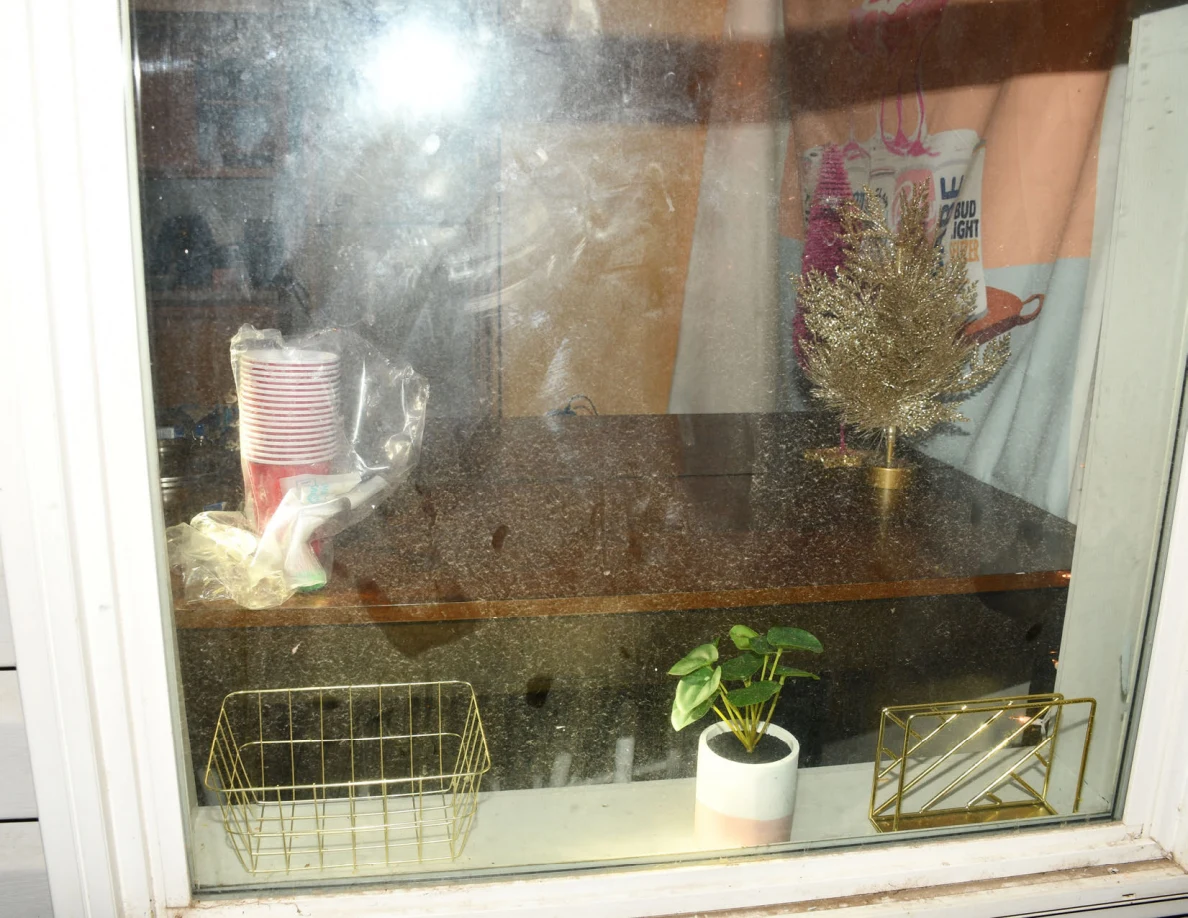 Window with visible smears; cups, table decorations and a potted plant visible through glass.
