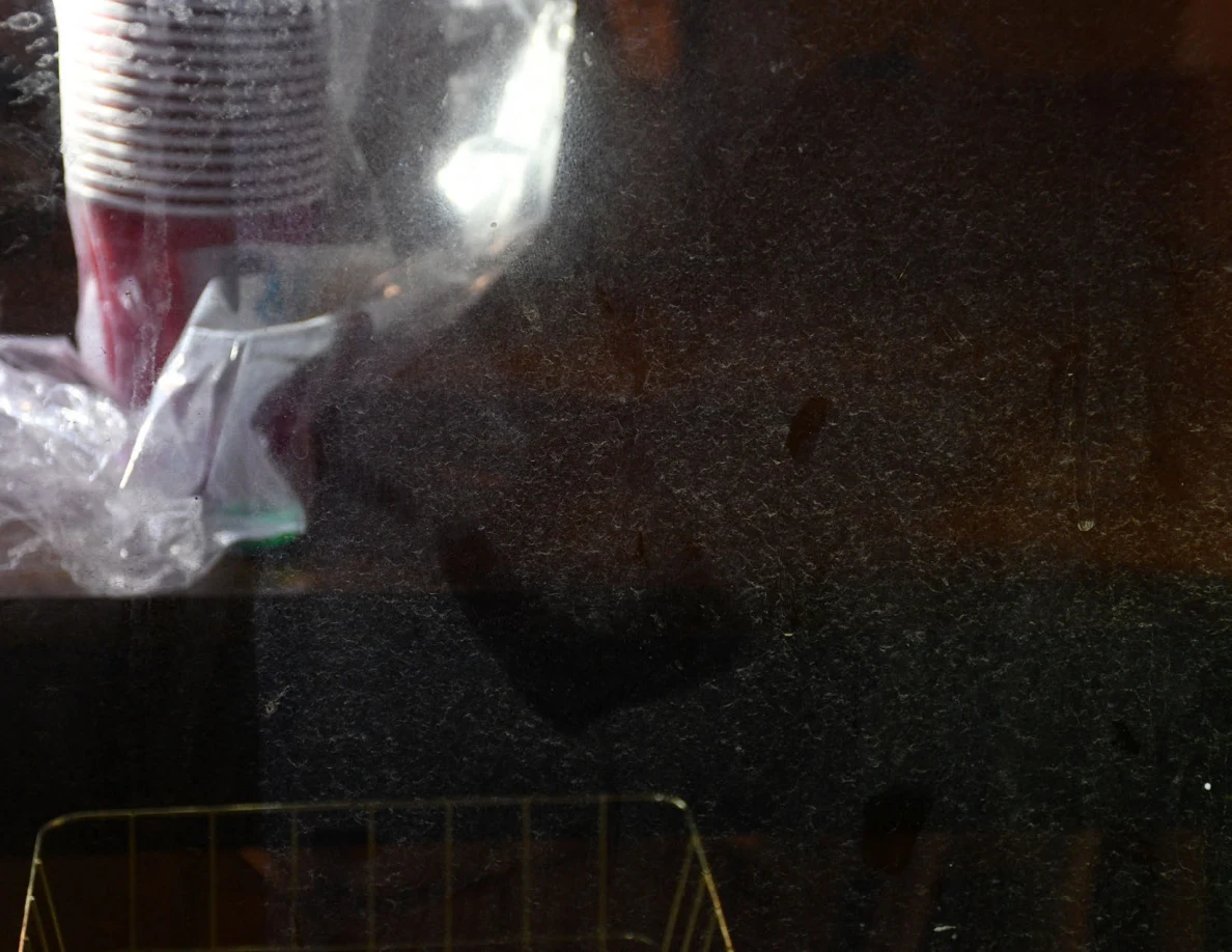 Close view of smears on window glass beside stacked cups.