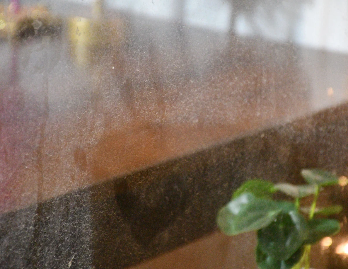 Close view of window glass and tabletop behind it.