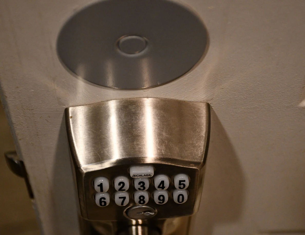 Close view of keypad door lock and round metal cover above it.