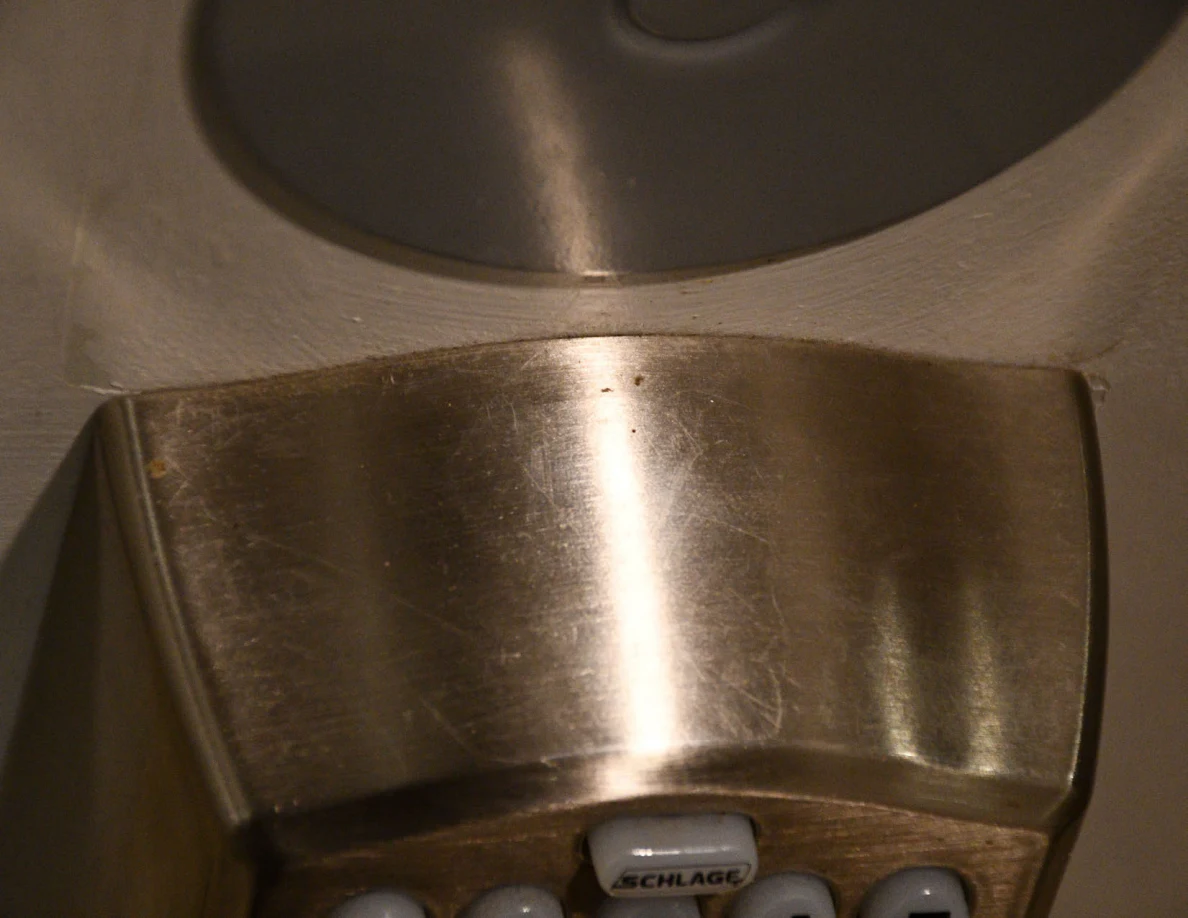 Close view of metal keypad-lock housing and round cover on a door.