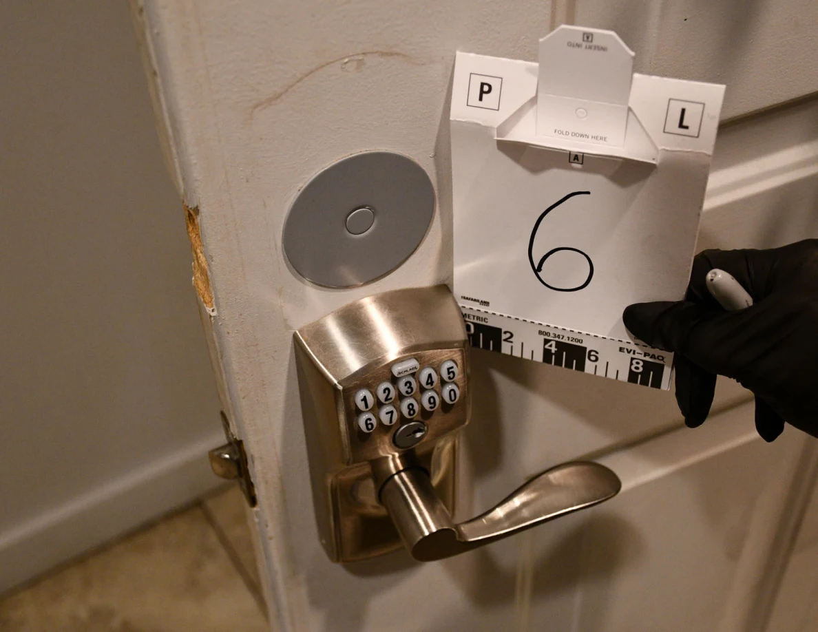 Gloved hand holding reference card 6 beside a keypad door lock.