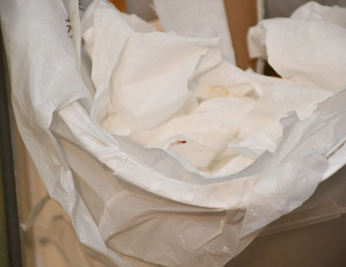 Close view of crumpled paper in a lined trash bin.