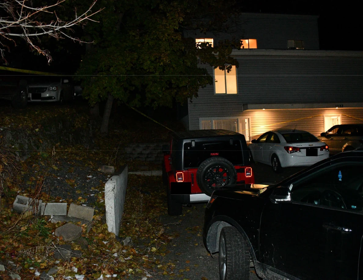 House exterior, red Jeep and other parked cars beneath trees.