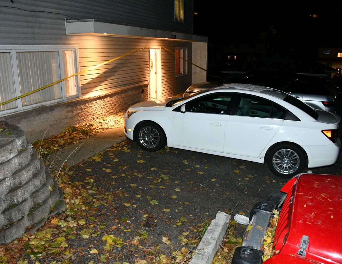 White car beside illuminated house entrance and yellow barrier tape.