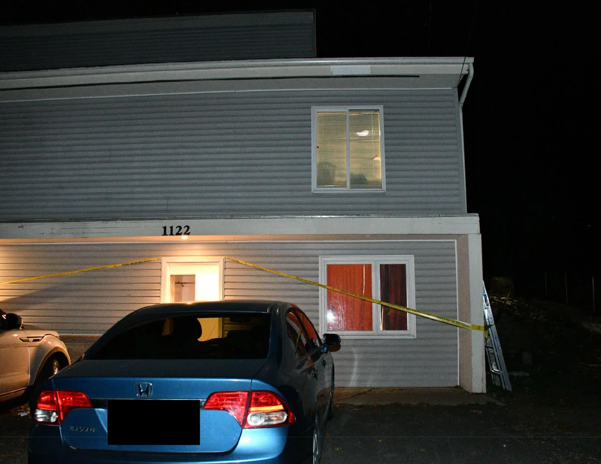 Blue sedan parked in front of open house entrance.