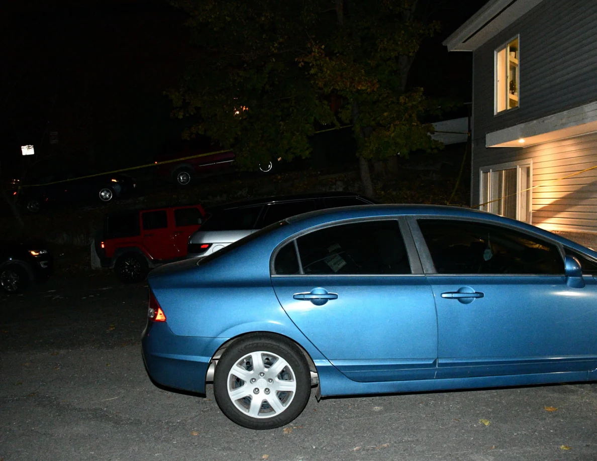 Side of a blue sedan parked beside a house.