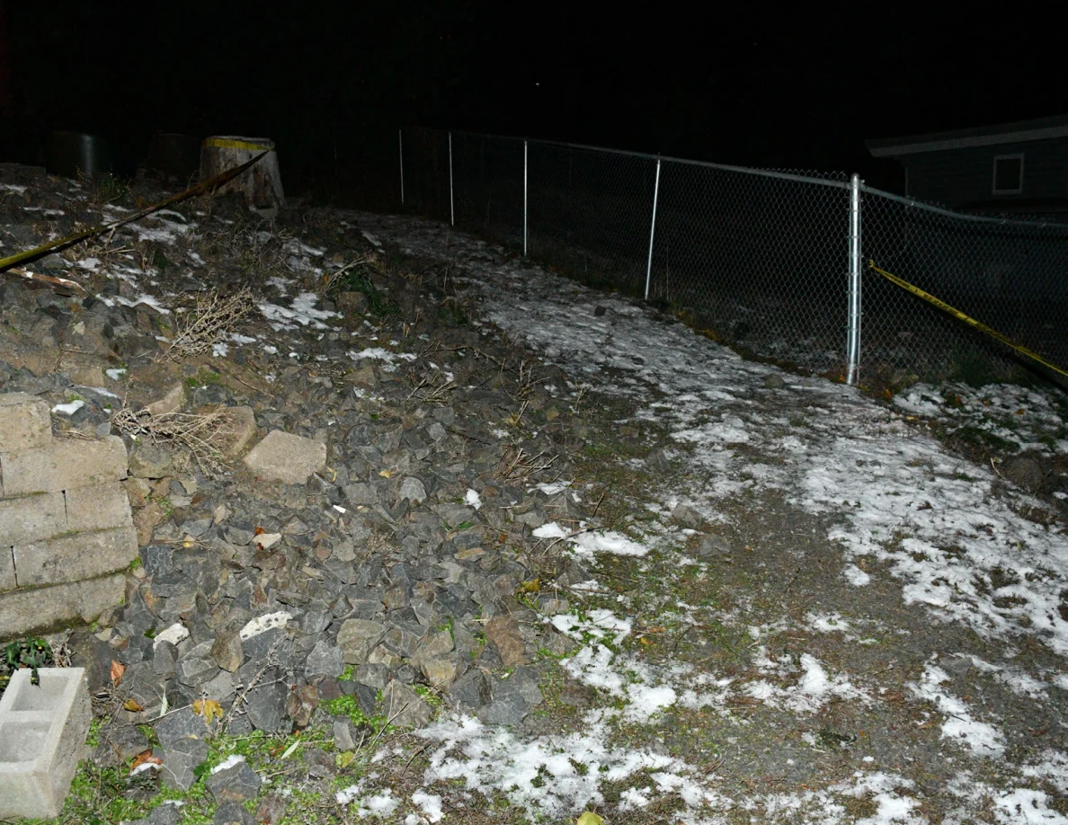 Snowy rocky slope beside a chain-link fence.